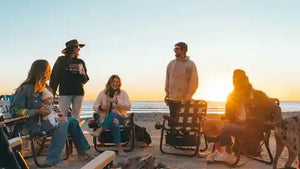 Group of people sitting on chairs by the beach at sunset